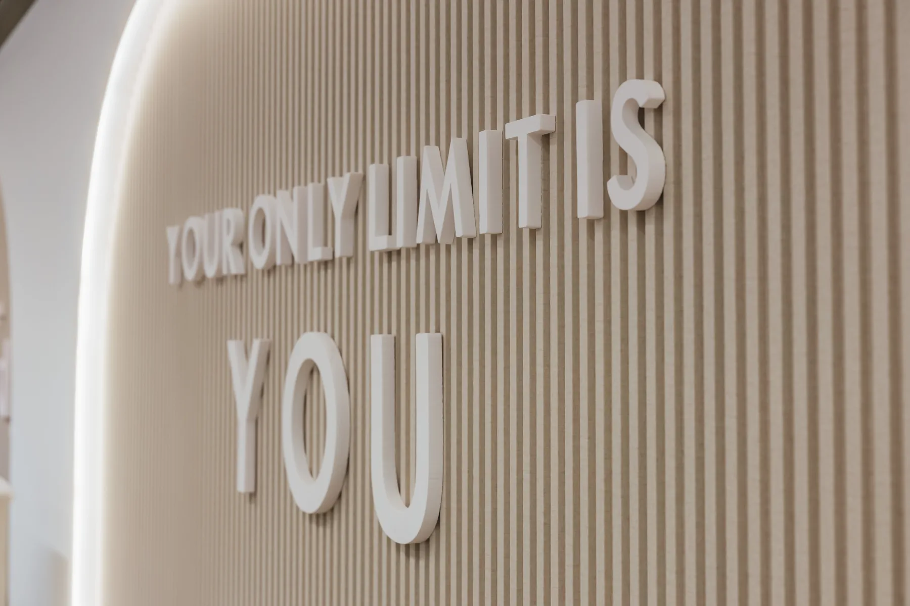 Zaobljeni zid teretane obložen WPC prečkicama sa natpisom